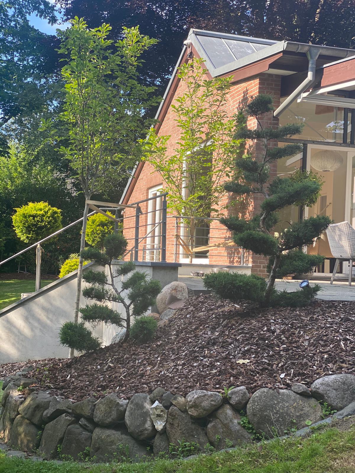 Ein Haus mit einer großen Steinmauer und einem kleinen Baum im Vordergrund.